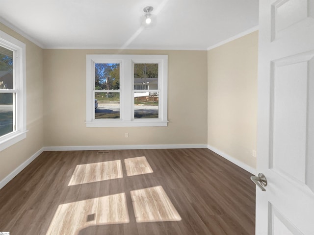 spare room with dark hardwood / wood-style flooring and crown molding