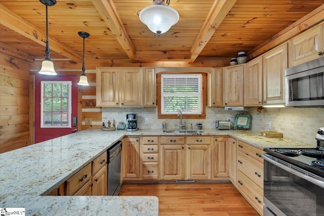 kitchen featuring appliances with stainless steel finishes, a wealth of natural light, wooden walls, and sink