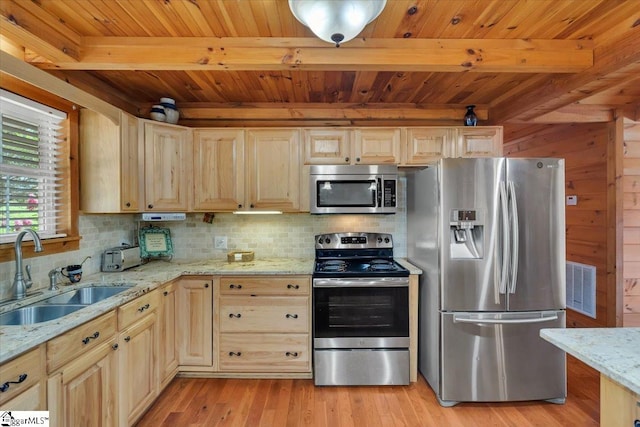 kitchen with beam ceiling, light stone countertops, sink, light hardwood / wood-style floors, and appliances with stainless steel finishes