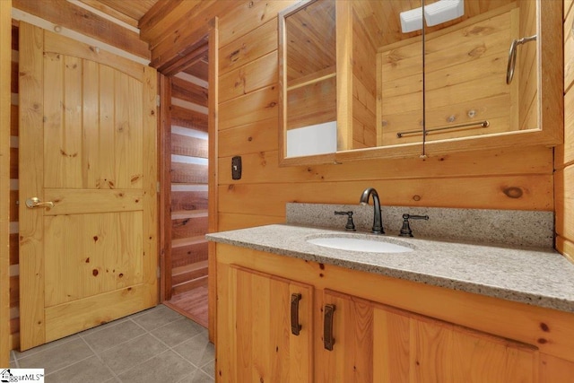 bathroom with tile patterned floors, wood walls, and vanity