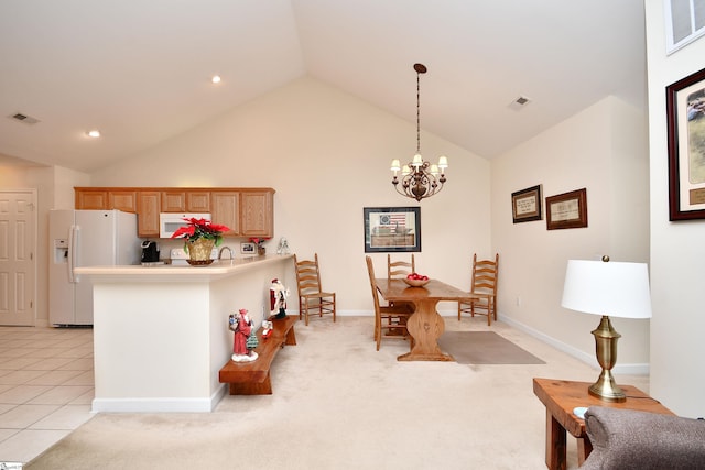 kitchen featuring kitchen peninsula, white appliances, light colored carpet, pendant lighting, and a notable chandelier