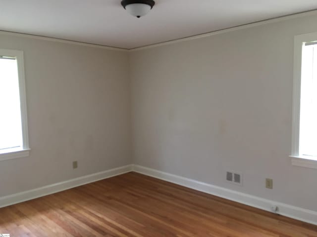 empty room with wood-type flooring and ornamental molding