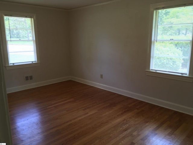 unfurnished room featuring dark hardwood / wood-style flooring, ornamental molding, and a wealth of natural light