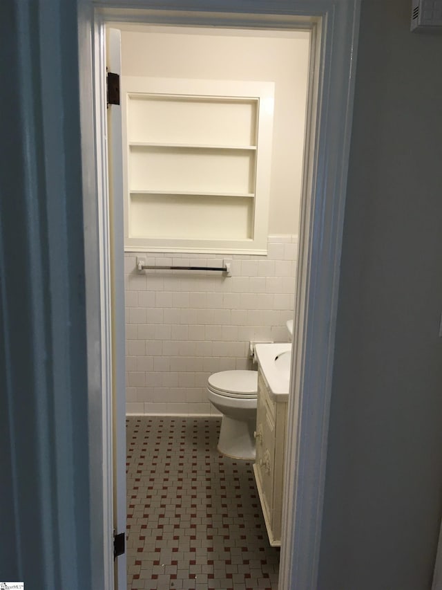 bathroom featuring vanity, tile patterned floors, toilet, built in features, and tile walls