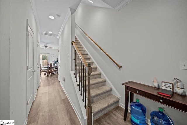 staircase featuring hardwood / wood-style flooring, ceiling fan, and ornamental molding