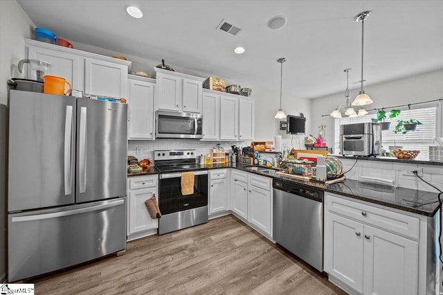 kitchen featuring light hardwood / wood-style floors, white cabinetry, stainless steel appliances, and hanging light fixtures