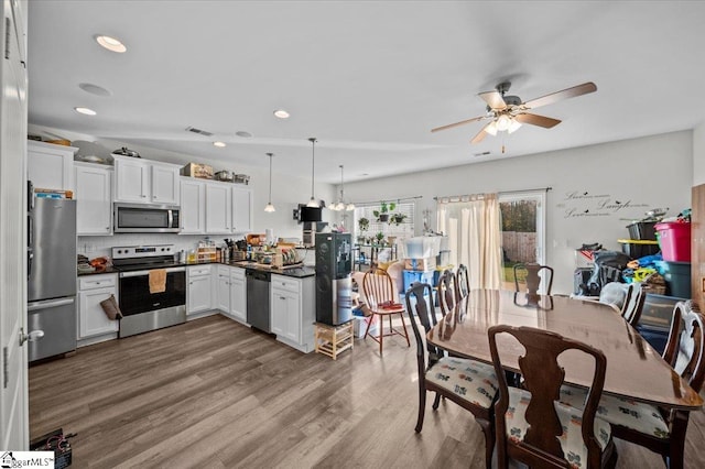 kitchen featuring stainless steel appliances, ceiling fan, pendant lighting, white cabinets, and hardwood / wood-style floors