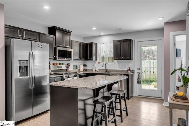 kitchen featuring sink, stainless steel appliances, a kitchen breakfast bar, light hardwood / wood-style floors, and a kitchen island