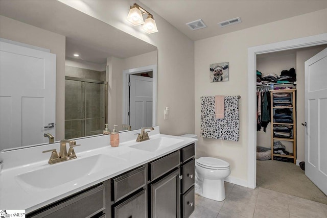 bathroom featuring tile patterned flooring, vanity, toilet, and a shower with door