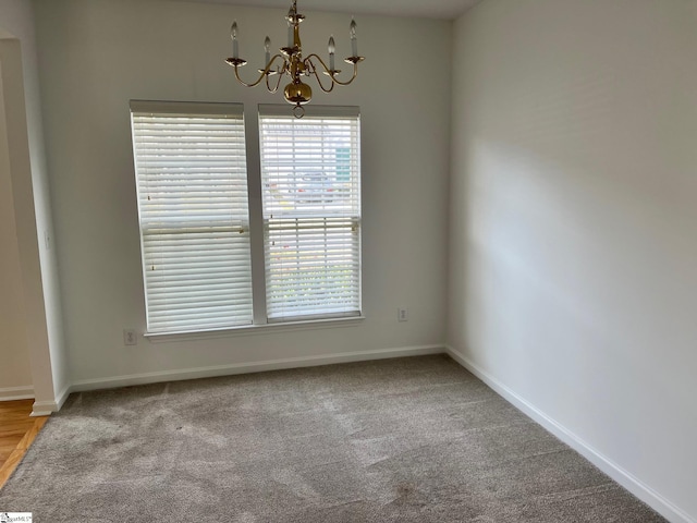 carpeted spare room with a chandelier