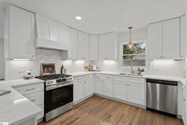 kitchen featuring white cabinets, sink, light hardwood / wood-style floors, custom range hood, and stainless steel appliances