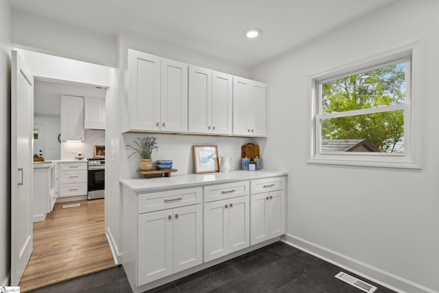 kitchen featuring white cabinets, decorative backsplash, dark hardwood / wood-style flooring, and stainless steel range oven