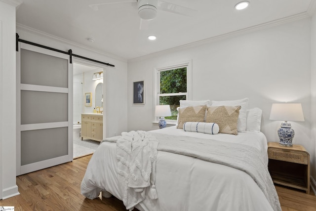 bedroom with ensuite bath, ceiling fan, crown molding, a barn door, and light hardwood / wood-style floors