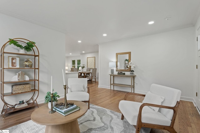 sitting room with ornamental molding and light hardwood / wood-style flooring