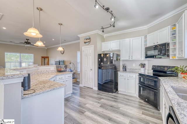 kitchen featuring hanging light fixtures, light stone counters, light hardwood / wood-style flooring, white cabinets, and black appliances