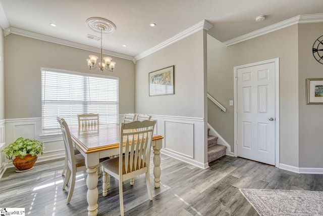 dining space with crown molding, light hardwood / wood-style floors, and a notable chandelier