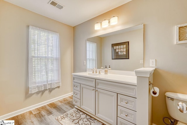 bathroom with toilet, vanity, and hardwood / wood-style flooring