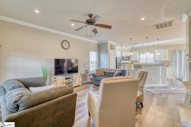 living room with light hardwood / wood-style floors, ceiling fan, and crown molding