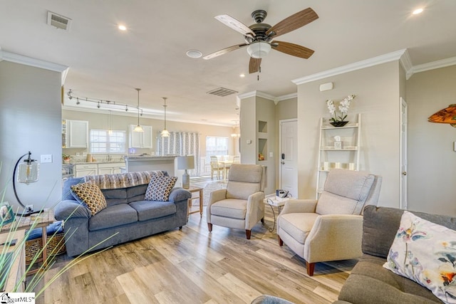 living room featuring a wealth of natural light, light wood-type flooring, and ornamental molding