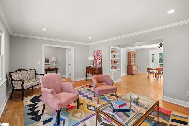 living room featuring built in features, ornamental molding, and light hardwood / wood-style flooring