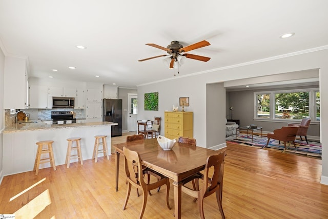 dining room featuring ceiling fan, light hardwood / wood-style flooring, sink, and ornamental molding