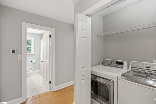 washroom with washing machine and dryer and light wood-type flooring