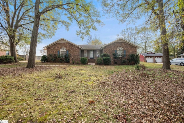 single story home featuring a garage, an outbuilding, and a front lawn