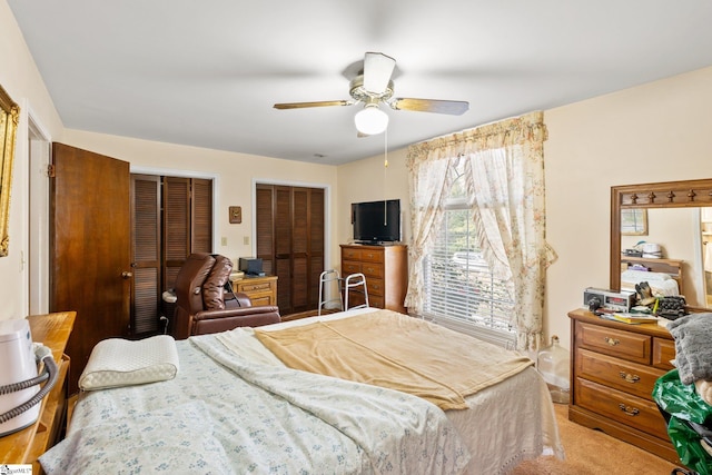 carpeted bedroom featuring multiple closets and ceiling fan