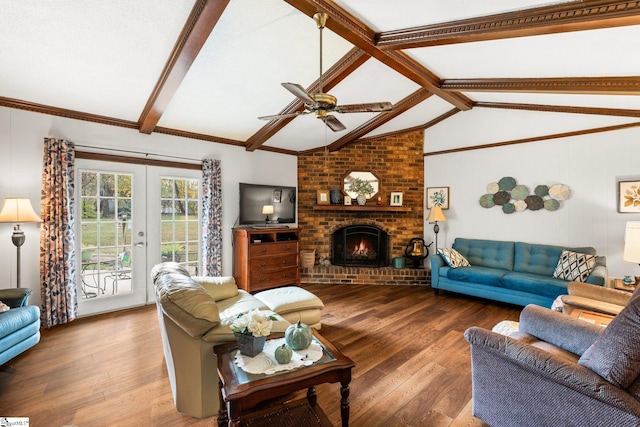 living room featuring hardwood / wood-style floors, vaulted ceiling with beams, ceiling fan, and a brick fireplace