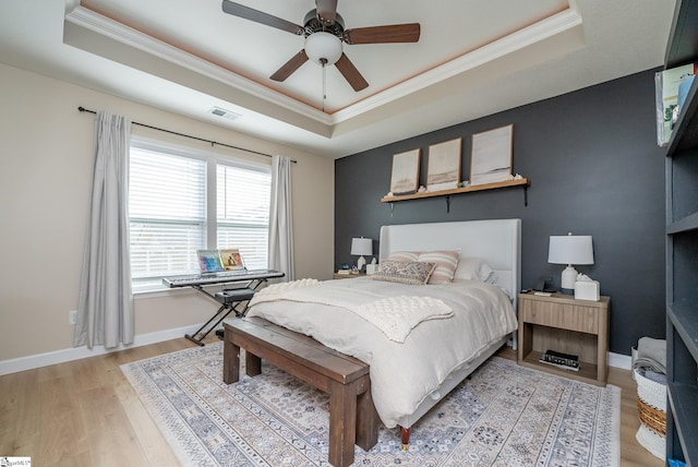 bedroom featuring a raised ceiling, ceiling fan, light hardwood / wood-style flooring, and crown molding