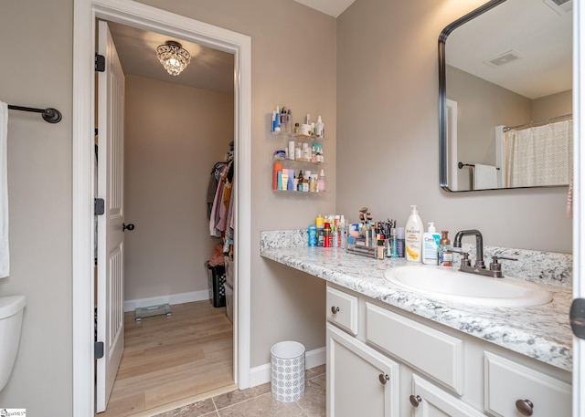 bathroom with toilet, vanity, and hardwood / wood-style flooring