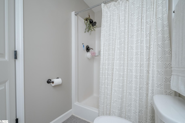 bathroom with a shower with shower curtain and toilet