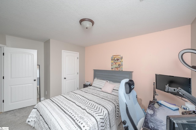 bedroom with light colored carpet and a textured ceiling