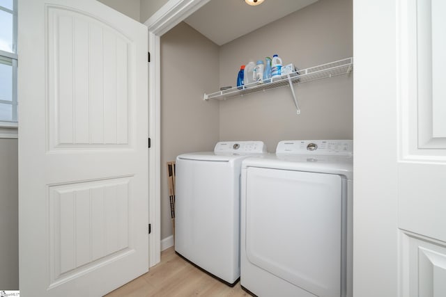 clothes washing area featuring washing machine and dryer and light hardwood / wood-style flooring