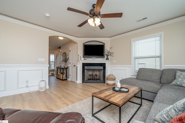 living room with ornamental molding, light wood-type flooring, and a healthy amount of sunlight