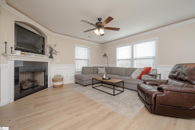 living room with a wealth of natural light, light hardwood / wood-style flooring, ceiling fan, and crown molding