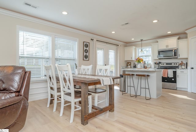 dining room featuring ornamental molding, light hardwood / wood-style floors, and a healthy amount of sunlight