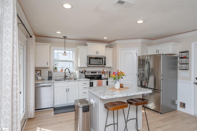 kitchen featuring white cabinetry, sink, a center island, hanging light fixtures, and appliances with stainless steel finishes