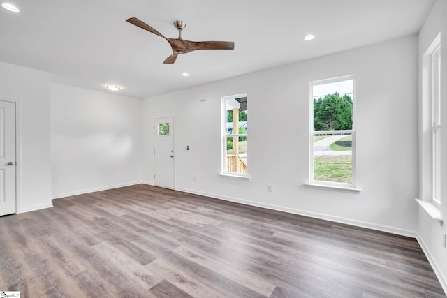 empty room with hardwood / wood-style floors, ceiling fan, and a healthy amount of sunlight