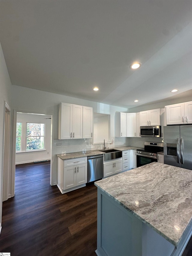 kitchen with sink, dark wood-type flooring, light stone counters, white cabinets, and appliances with stainless steel finishes