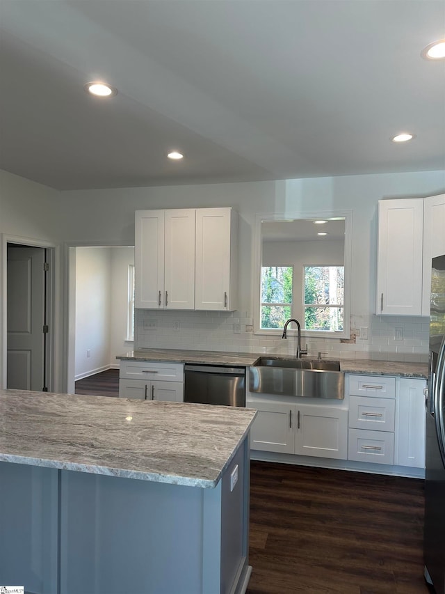 kitchen with dark hardwood / wood-style flooring, light stone counters, stainless steel appliances, sink, and white cabinets