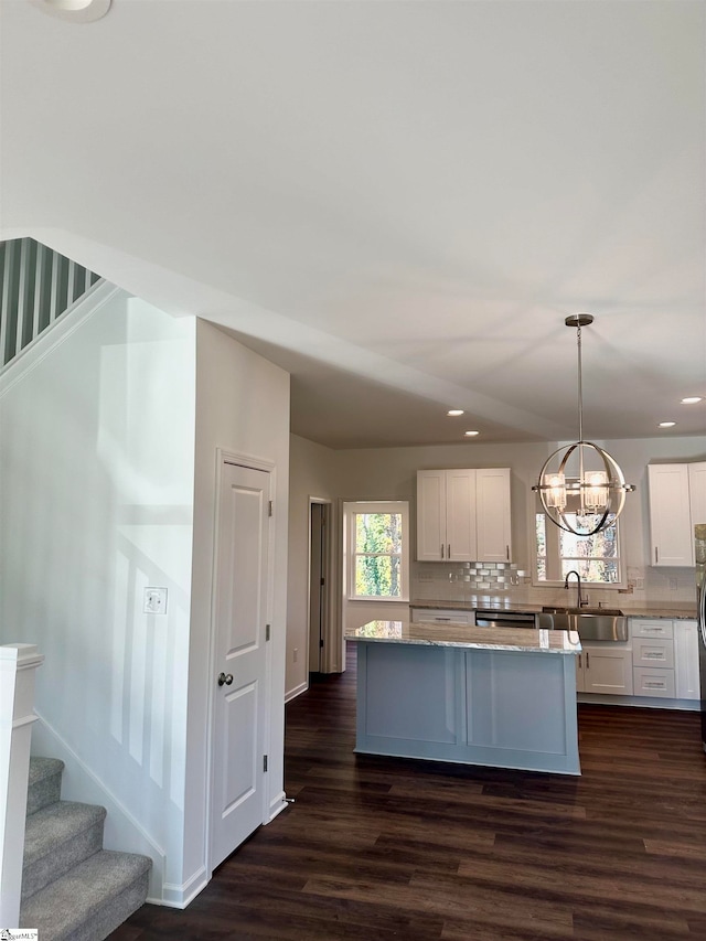 kitchen with dark hardwood / wood-style flooring, sink, white cabinets, and decorative light fixtures