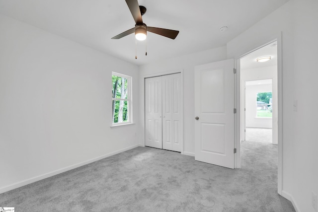 unfurnished bedroom with ceiling fan, light colored carpet, and a closet