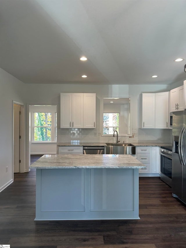 kitchen with sink, light stone counters, dark hardwood / wood-style floors, white cabinets, and appliances with stainless steel finishes