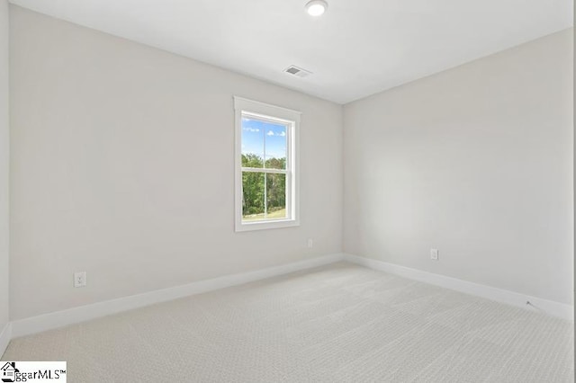 empty room featuring baseboards, visible vents, and light carpet