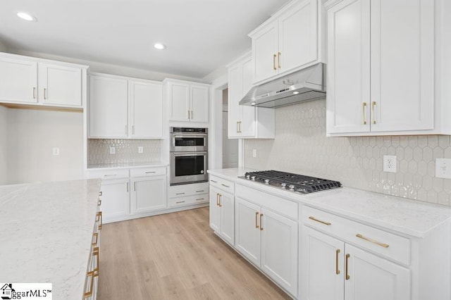 kitchen featuring backsplash, under cabinet range hood, stainless steel appliances, and white cabinetry