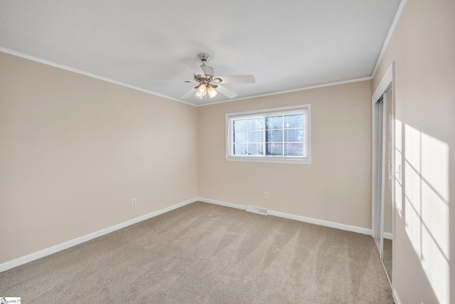 spare room featuring light colored carpet, ceiling fan, and crown molding