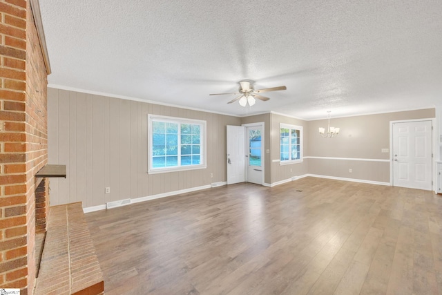 unfurnished living room with hardwood / wood-style floors, ceiling fan with notable chandelier, ornamental molding, and a wealth of natural light