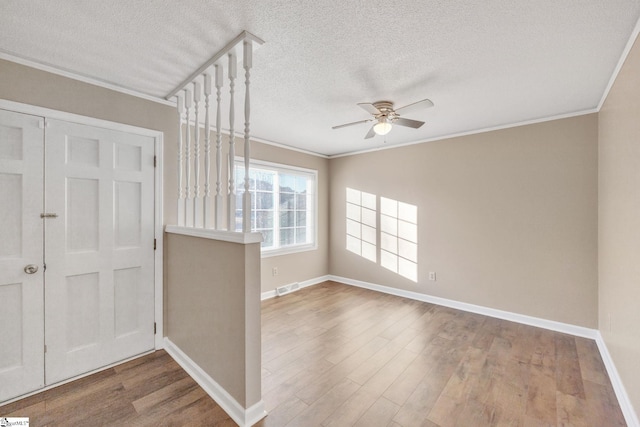 foyer featuring wood-type flooring, a textured ceiling, ceiling fan, and crown molding