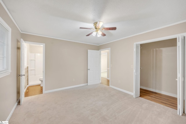 unfurnished bedroom featuring ceiling fan, ornamental molding, a textured ceiling, connected bathroom, and light colored carpet